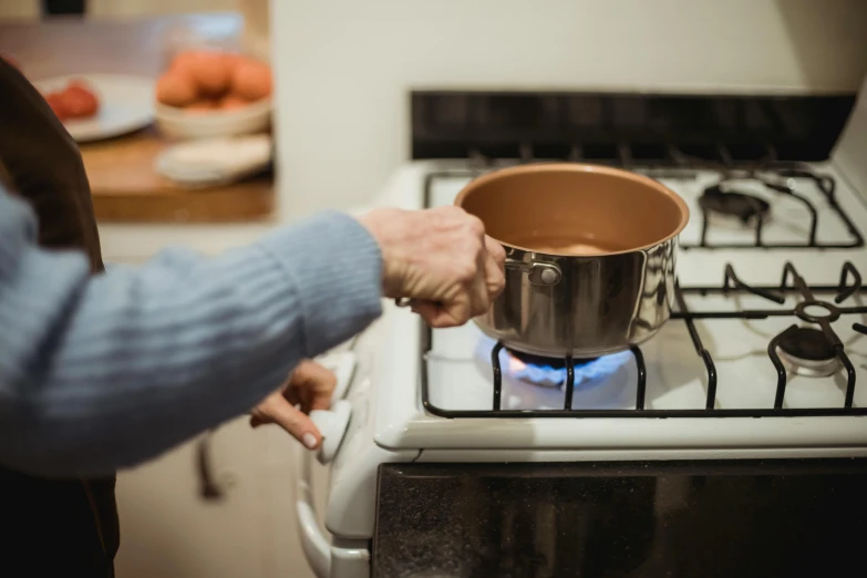 a person holding a pot on top of a stove, brown, profile image, thumbnail, shot on sony a 7