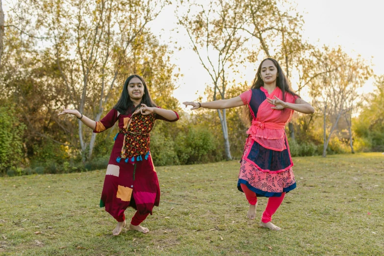 a couple of women standing on top of a lush green field, an album cover, hurufiyya, anjali mudra, red and blue garments, performance, square