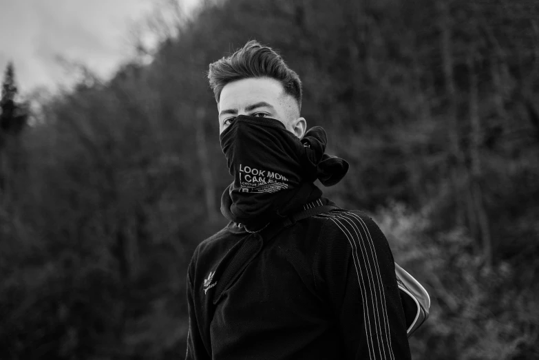 a black and white photo of a man covering his face, a black and white photo, by Adam Marczyński, pexels contest winner, graffiti, techwear clothes, black bandana mask, cai xukun, in glitchart jared forest