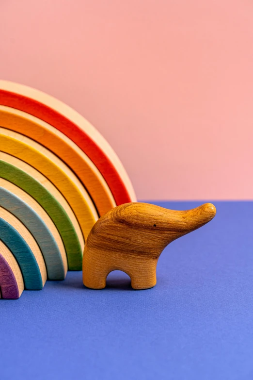 a wooden elephant and a rainbow on a blue surface, trending on unsplash, dinosaur wooden statue, 2 1 0 mm, various sizes, curved