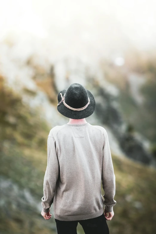 a man wearing a hat standing on top of a mountain, by Anna Boch, trending on unsplash, renaissance, back of head, soft and muted colors, portrait mode photo, photo of a woman