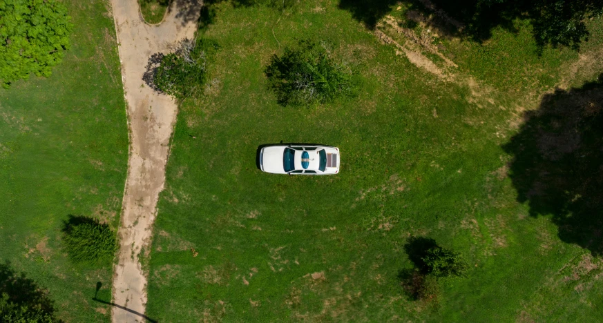 an aerial view of a car driving down a dirt road, on a green lawn, curious, mechanics, old abandoned car sinking