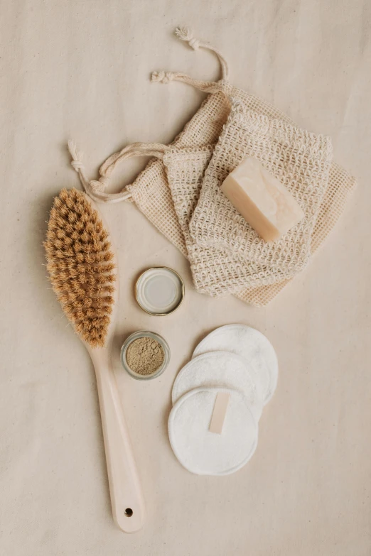 a wooden brush sitting on top of a white sheet, by Nicolette Macnamara, pexels, holding mesh bag with bagels, clean face and body skin, various items, soap