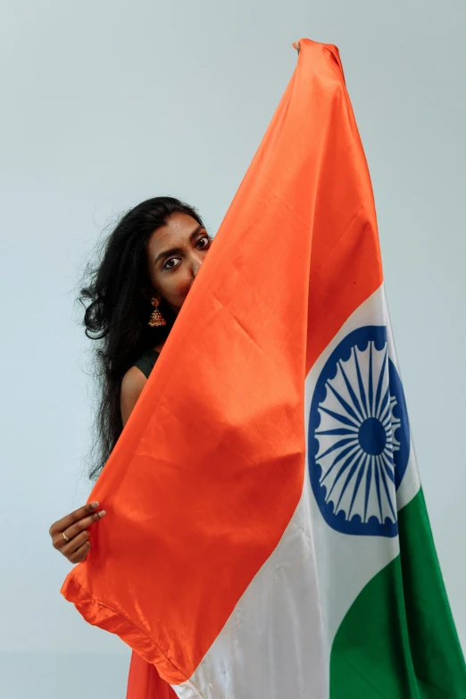 a woman holding an indian flag in front of her face, an album cover, pexels contest winner, standing sideways, ( ( theatrical ) ), 2070, patriotism