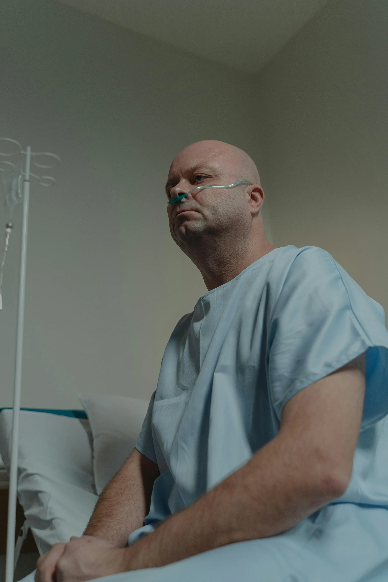 a man is sitting in a hospital bed, hyperrealism, cinestill colour cinematography, bald, promo image, iv pole