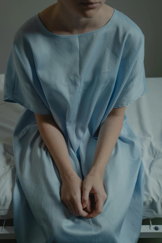 a woman in a hospital gown sitting on a bed, trending on reddit, centered shot, low quality photo, pastel', medical image