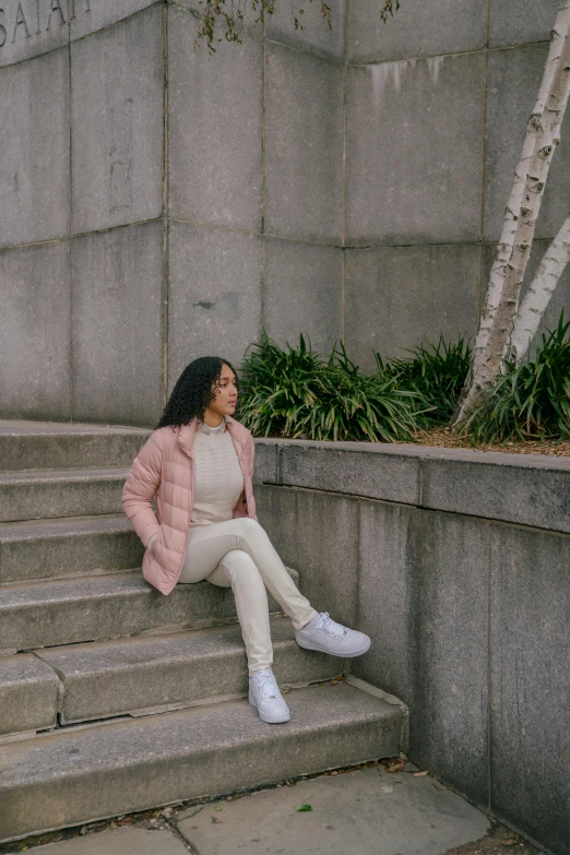 a woman sitting on the steps of a building, by Dulah Marie Evans, trending on unsplash, visual art, wearing a light - pink suit, model wears a puffer jacket, full body cute young lady, low quality footage