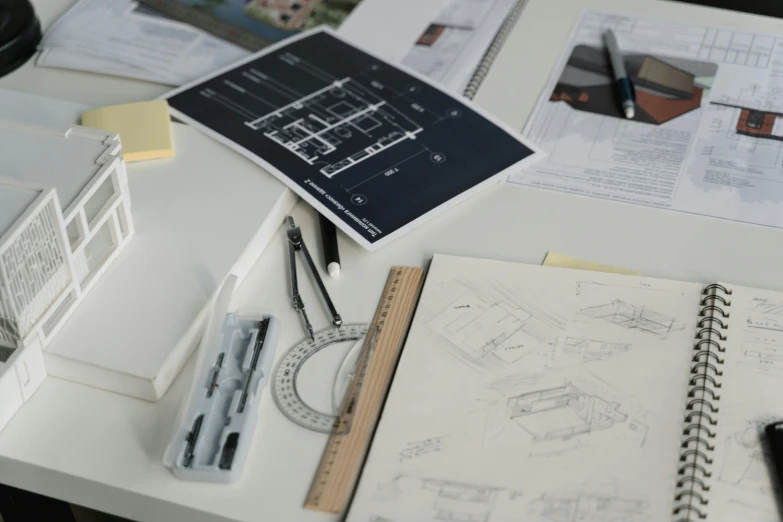 a desk topped with lots of papers and a cell phone, a drawing, behance, overall architectural design, foster and partners, small details, drawing pictures on a notebook