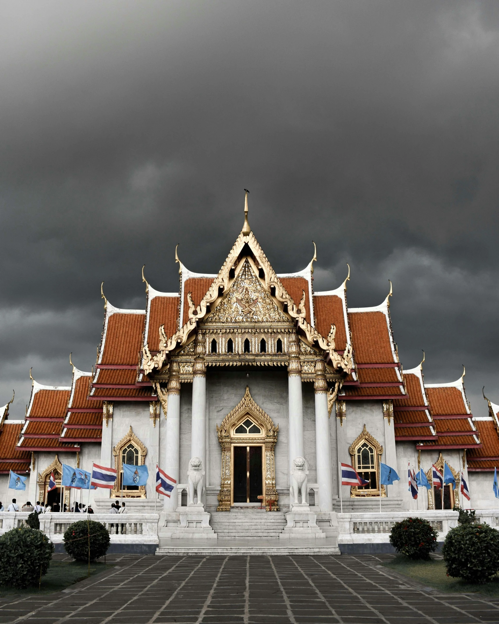 a large white building with a red roof, a marble sculpture, inspired by Thomas Struth, unsplash contest winner, thai temple, grey skies with two rainbows, ominous clouds, album cover