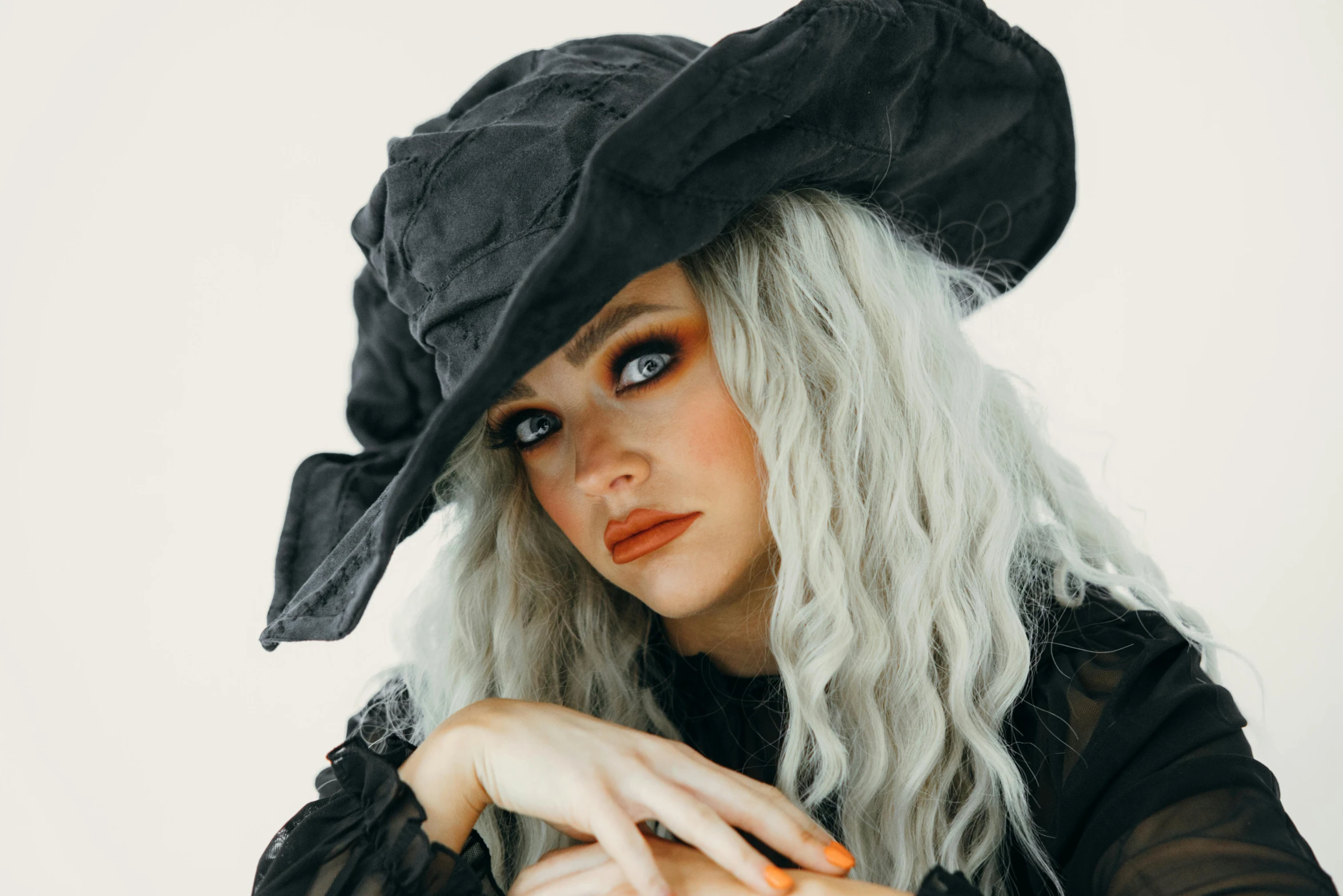 a woman with long white hair wearing a black hat, trending on pexels, lowbrow, curly blonde hair | d & d, witch clothes, square, ashy