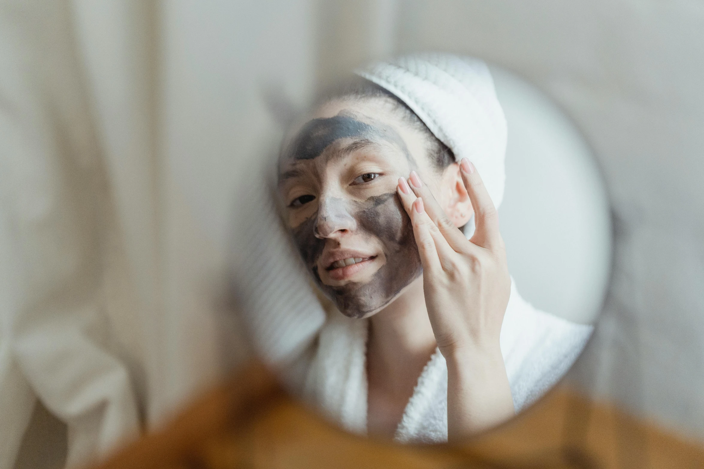 a woman that is standing in front of a mirror, mud on face, face mask, wearing a grey robe, beauty woman with detailed faces