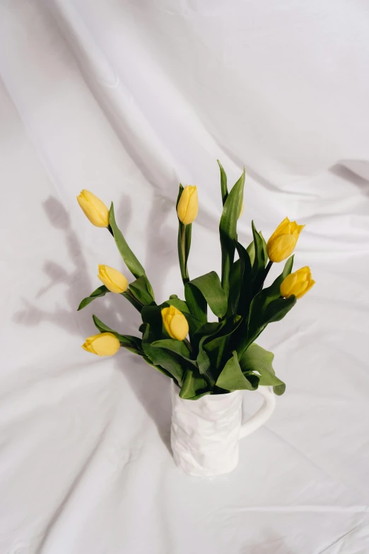 a bouquet of yellow tulips in a white vase, inspired by Judy Takács, unsplash, romanticism, marbled, angled shot, full product shot, group of seven