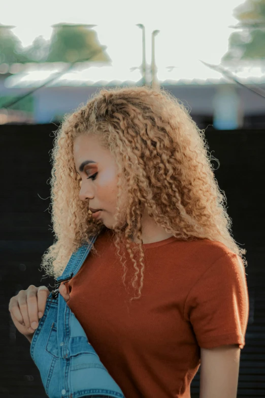 a woman with curly hair wearing a denim jacket, trending on pexels, light gold hair, paul barson, african american girl, rusty colored long hair