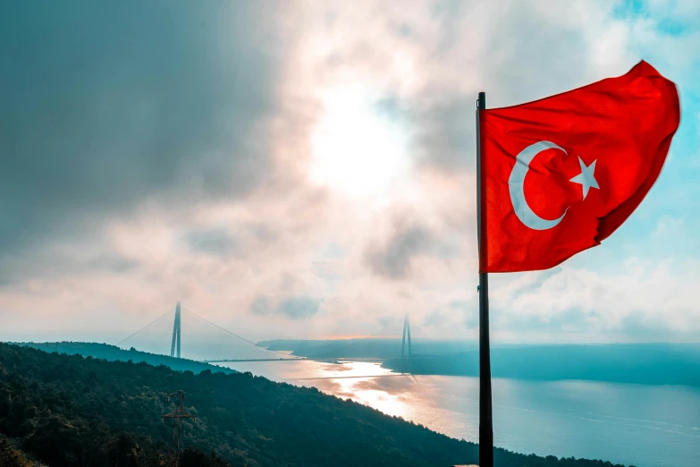 a turkish flag flying in front of a large body of water, on a canva, thumbnail, bridge, trident