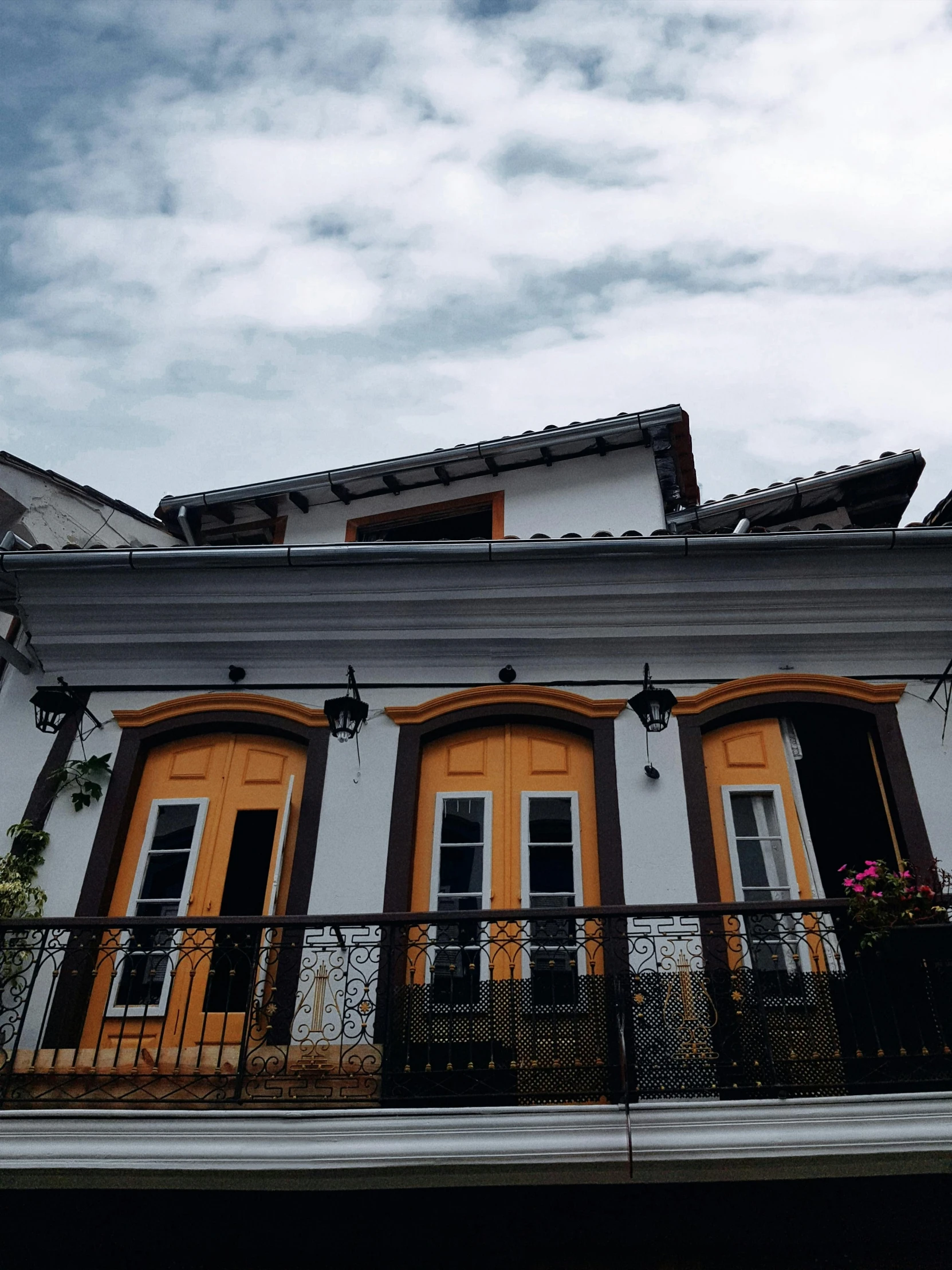 a white and orange building with a balcony and balconies, unsplash, quito school, overcast! cinematic focus, village house, black and yellow color scheme, snapchat photo