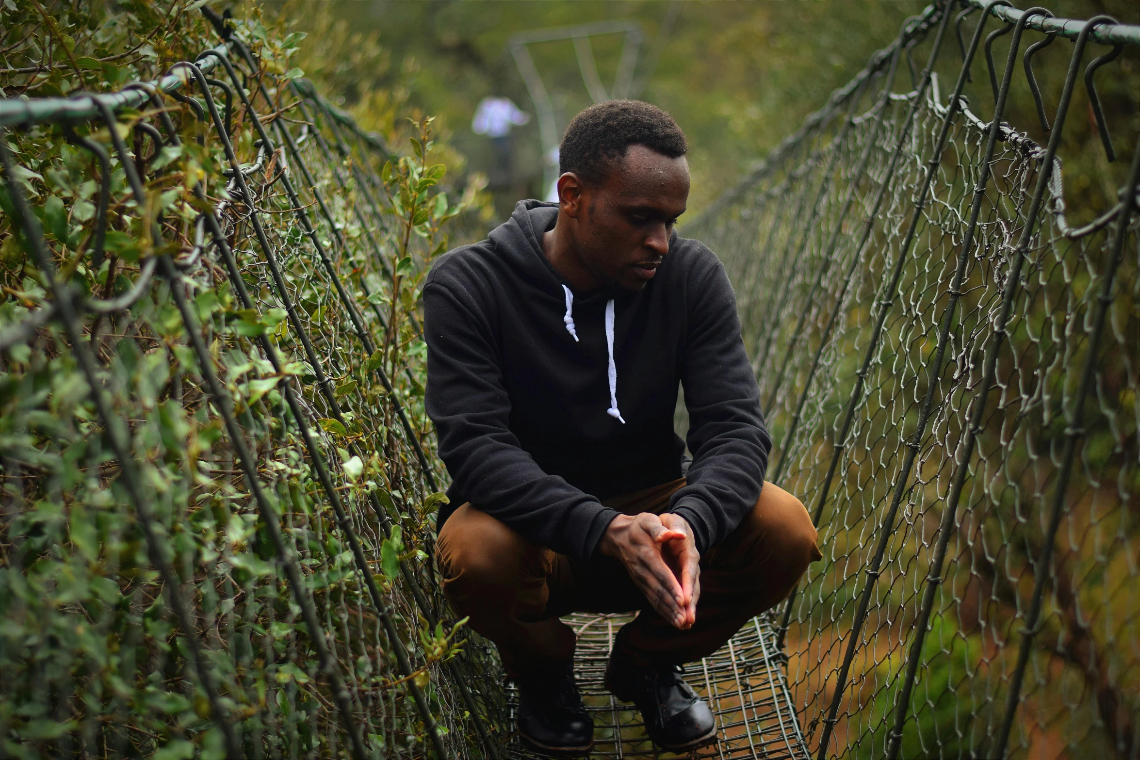 a man sitting on top of a wooden bridge, an album cover, pexels contest winner, hurufiyya, unmistakably kenyan, avatar image, serious expression, award winning movie still