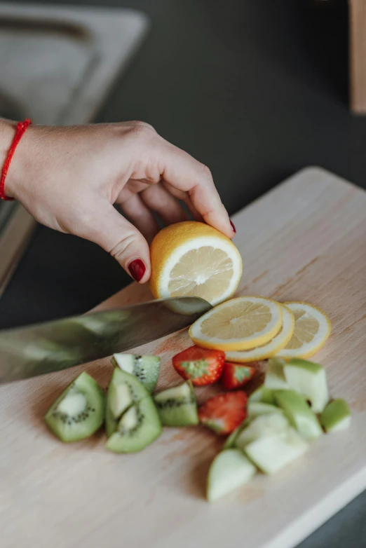 a person cutting a lemon on a cutting board, pexels contest winner, kiwi, veggies, mint, partially cupping her hands