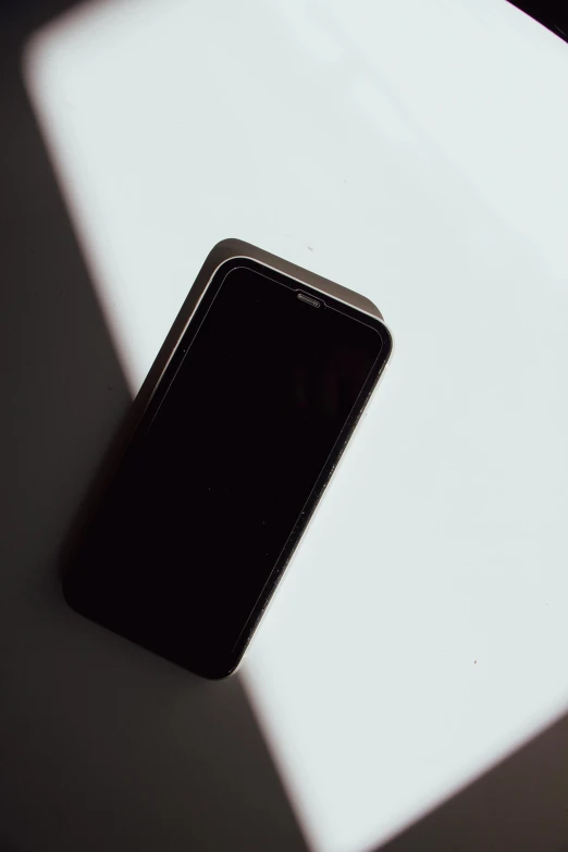 a cell phone sitting on top of a table, trending on unsplash, minimalism, shadowed face, black plastic, 1 2 9 7, professional iphone photo