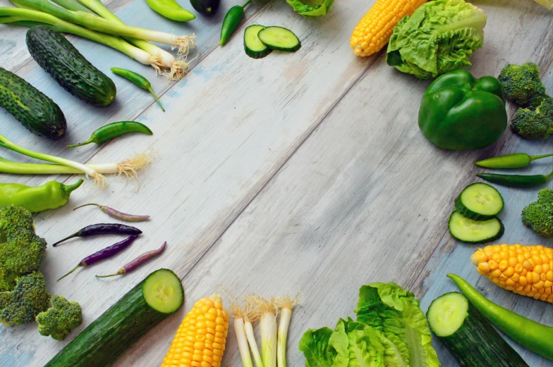 a wooden table topped with lots of different types of vegetables, unsplash, brand colours are green and blue, background image, cucumber, green flags