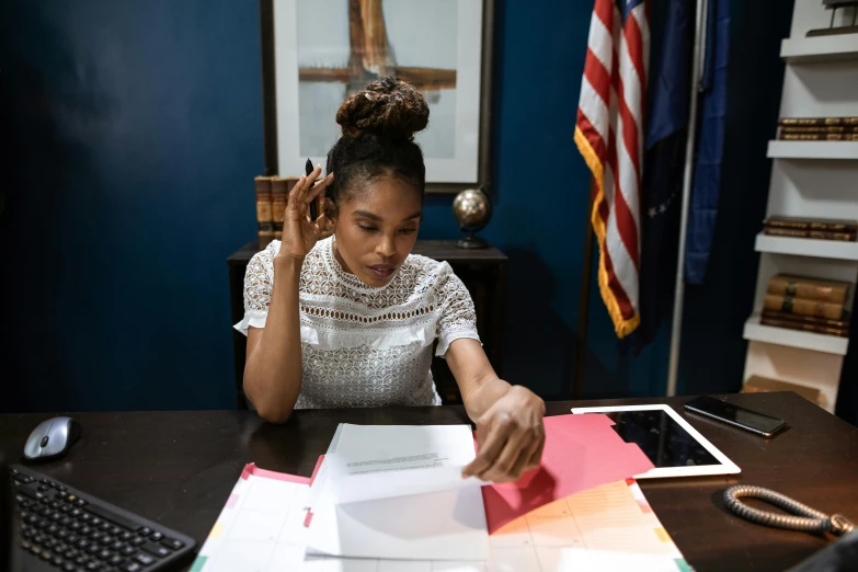 a woman sitting at a desk in front of a computer, by Dan Frazier, pexels contest winner, ashteroth, holding court, papers on table, promotional image