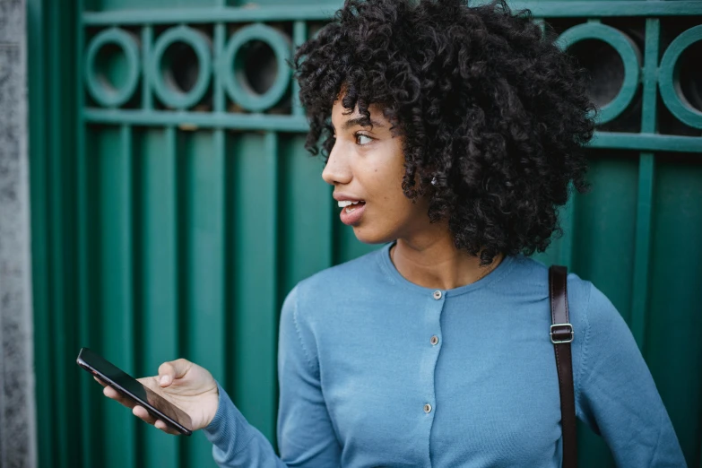 a close up of a person holding a cell phone, trending on pexels, happening, mixed-race woman, teal, curly black hair, walking