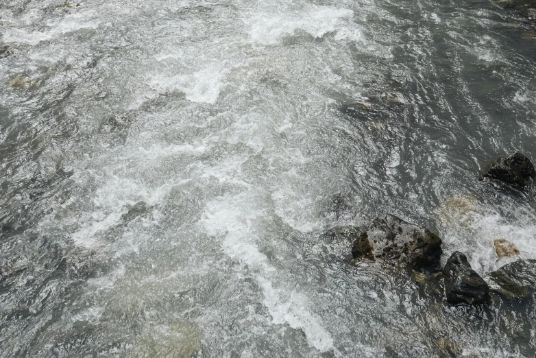 a man riding a surfboard on top of a river, an album cover, inspired by Andreas Gursky, pexels, running water, detail texture, river stream, gray