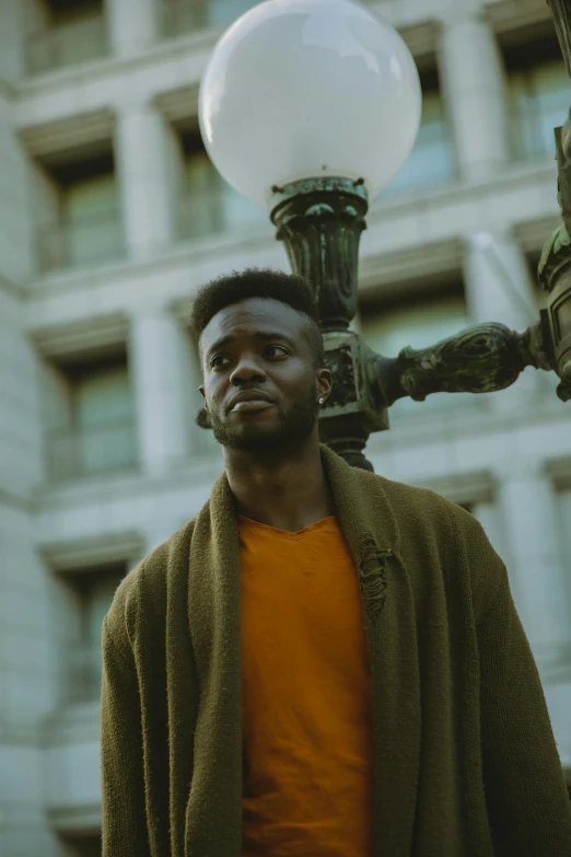 a man standing in front of a street light, an album cover, pexels contest winner, jaylen brown, he is wearing a brown sweater, standing in a city center, looking off to the side