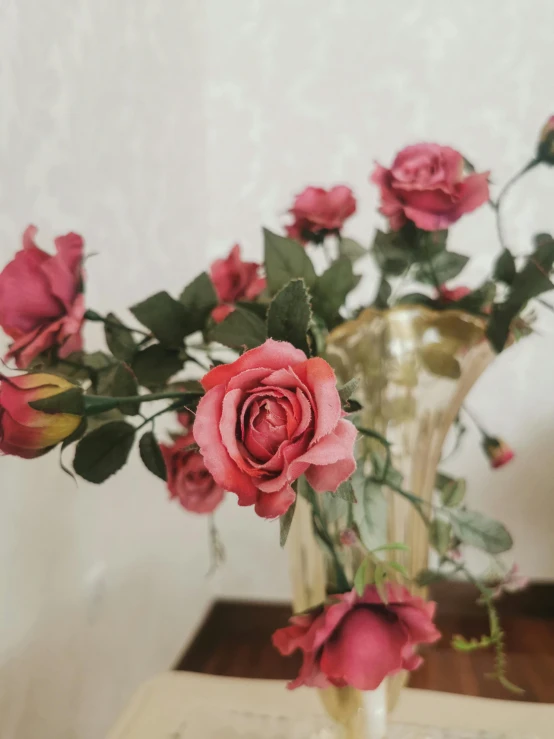 a vase filled with pink roses sitting on top of a table, inspired by Elsa Bleda, pexels, faded red and yelow, 🎀 🧟 🍓 🧚, vintage closeup photograph, low quality photo