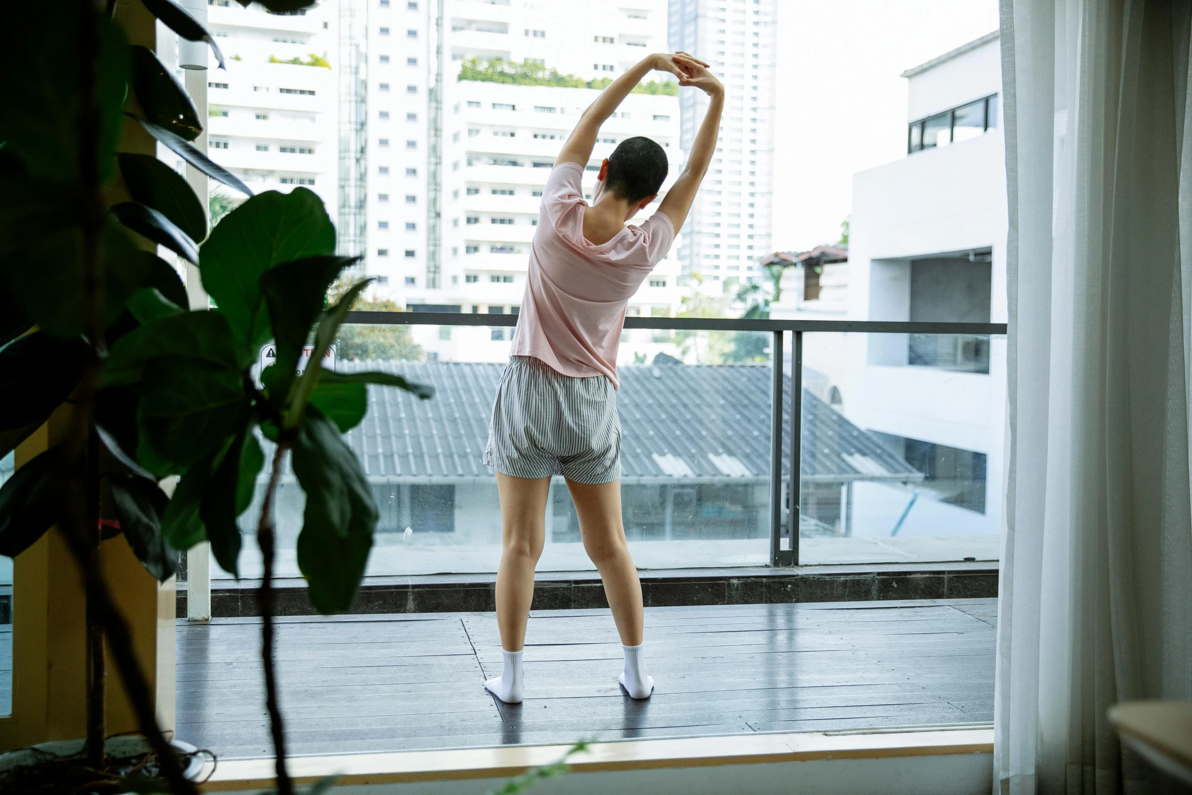 a woman standing on top of a wooden floor next to a window, happening, working out, waking up, balcony, joy ang