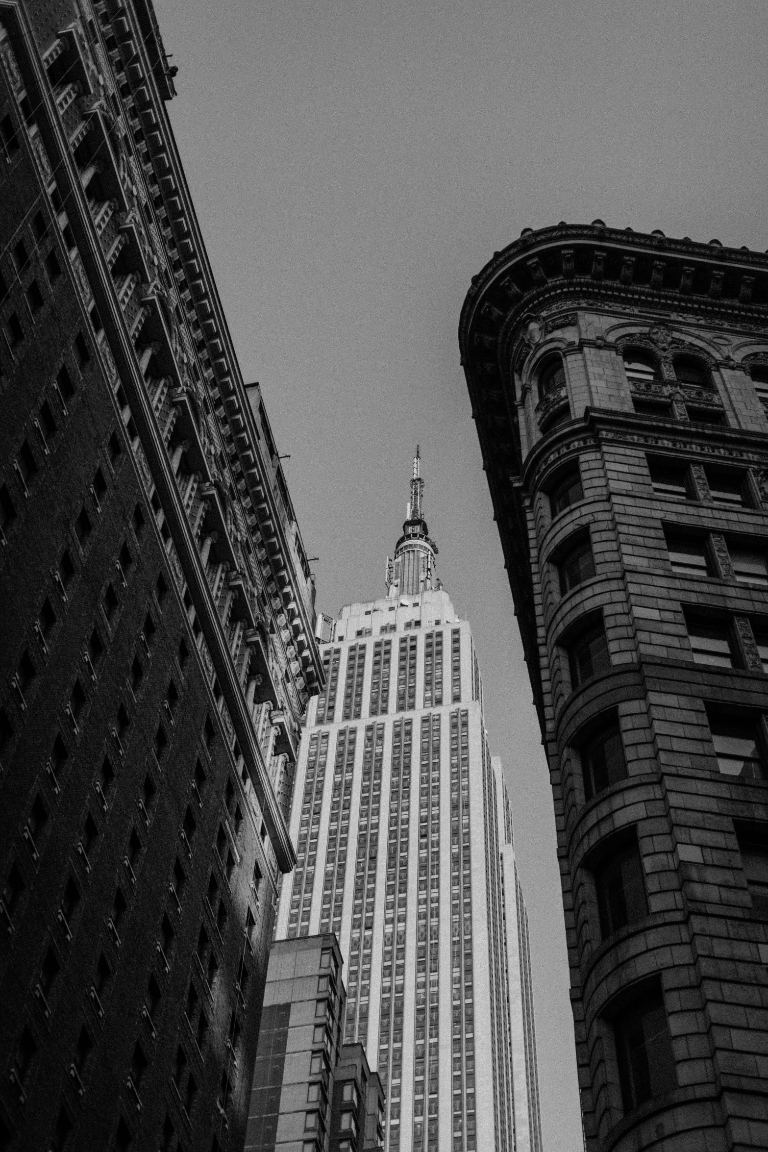 a black and white photo of the empire state building, unsplash contest winner, vorticism, other smaller buildings, taken in the late 2000s, art deco office buildings, mossy buildings