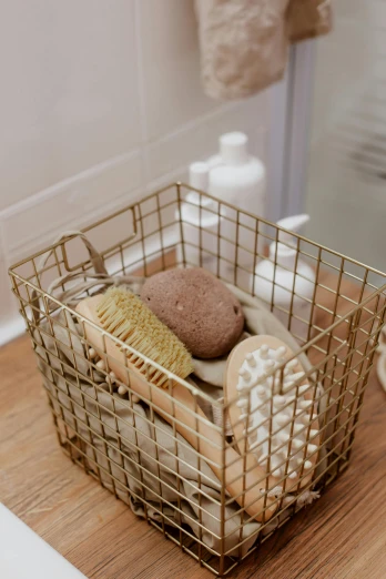 a metal basket sitting on top of a wooden counter, pexels, in bathroom, beige and gold tones, sponge, curated collections