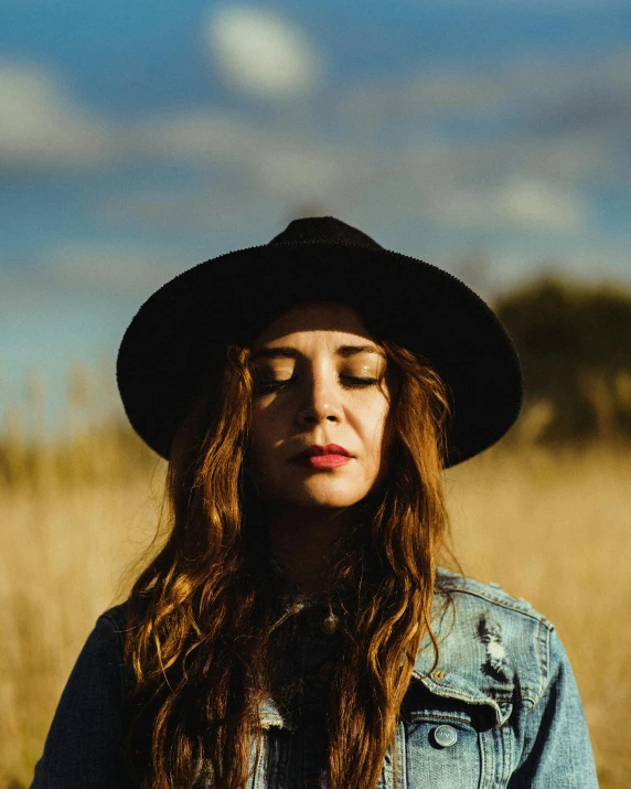 a woman wearing a hat standing in a field, an album cover, pexels contest winner, antipodeans, crisp face, wild ginger hair, profile image, squinting at high noon