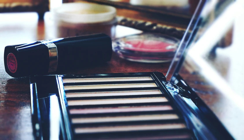 a close up of a lipstick and a mirror on a table, smokey eye, stripe over eye, ((oversaturated)), vintage colours