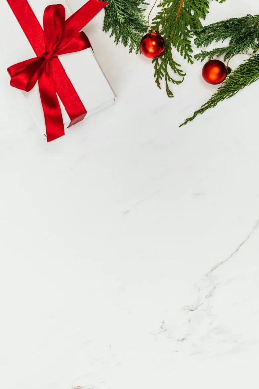 a gift box sitting on top of a table next to a christmas tree, a still life, inspired by Ernest William Christmas, trending on pexels, white marble texture, background image, digital image, splash image