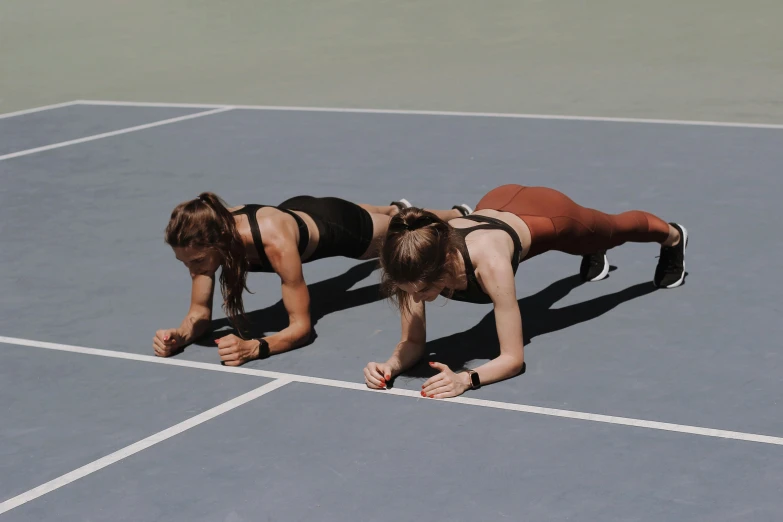 two women doing push ups on a tennis court, by Emma Andijewska, pexels contest winner, physical : tinyest midriff ever, running sequence, thumbnail, taken on iphone 14 pro