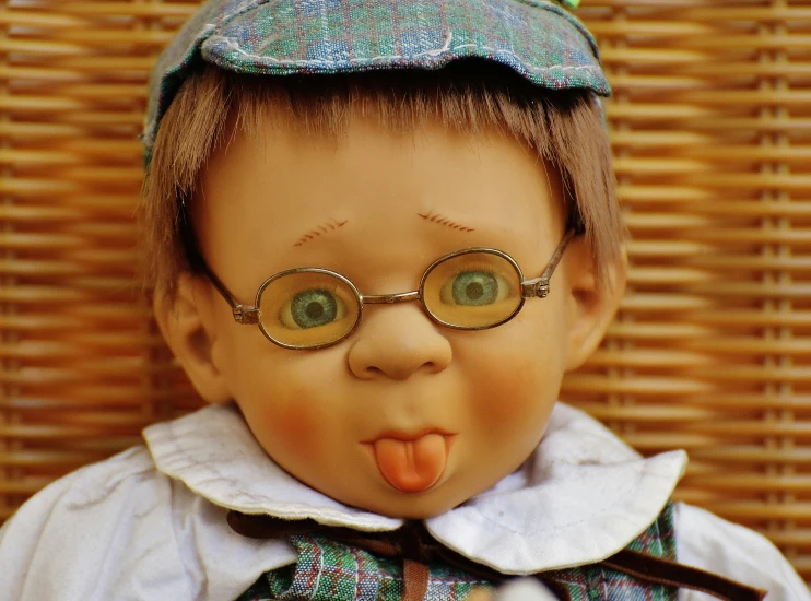 a close up of a doll wearing glasses and a hat, by Kurt Seligmann, pixabay contest winner, boy with neutral face, 1997, licking tongue, biedermeier