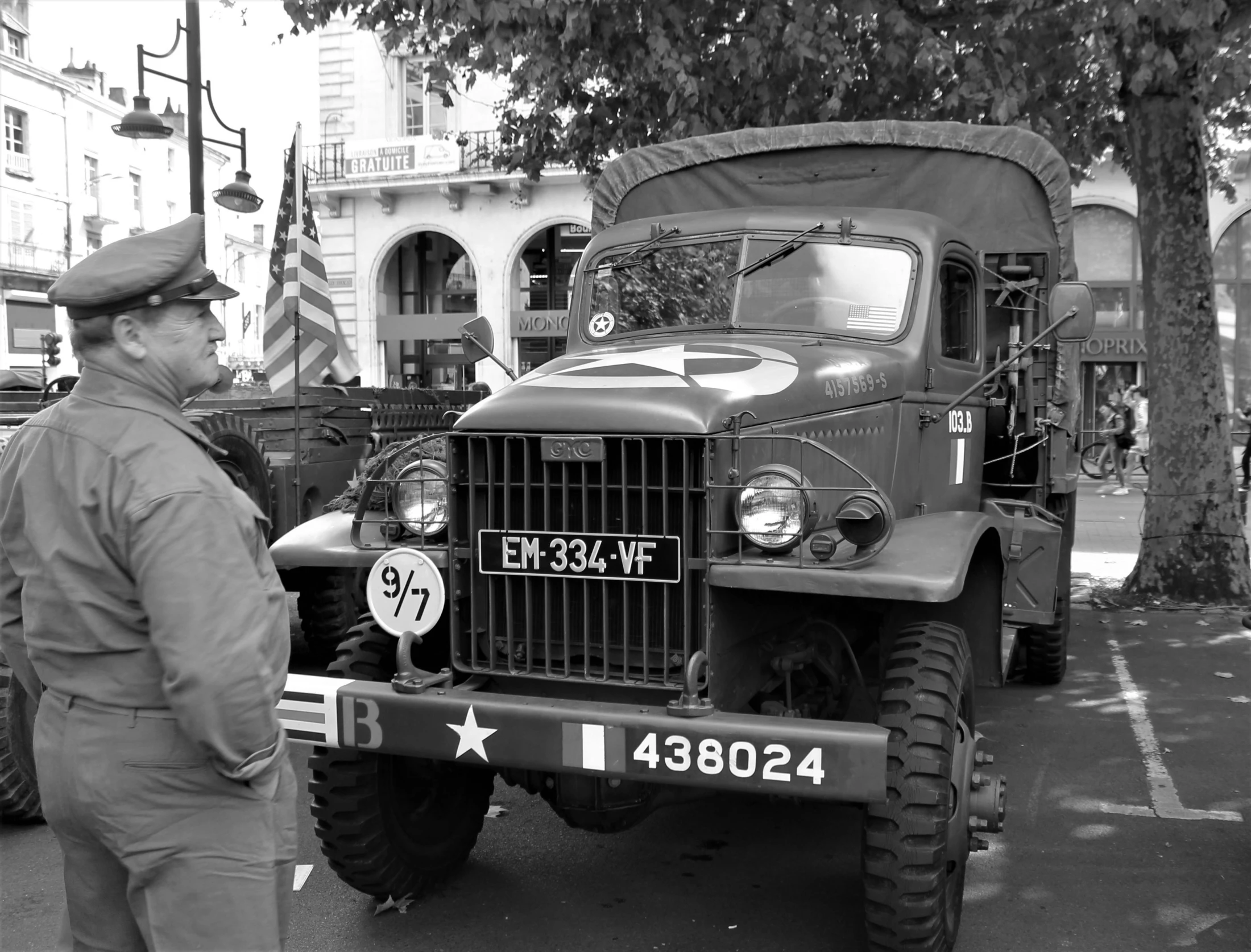 a black and white photo of a man standing next to a truck, by Róbert Berény, flickr, military parade, bocage, by greg rutkowski, square