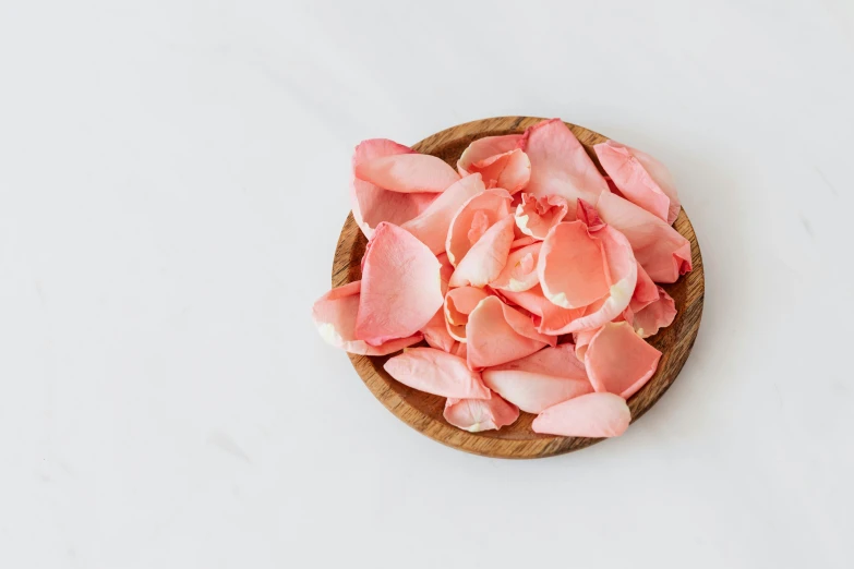 a wooden bowl filled with pink petals on a white surface, ((pink)), organics, fan favorite, flattened