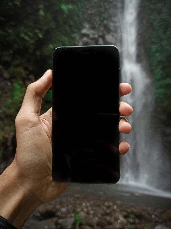 a person taking a picture of a waterfall, black oled background, tall, phone quality, in a jungle environment