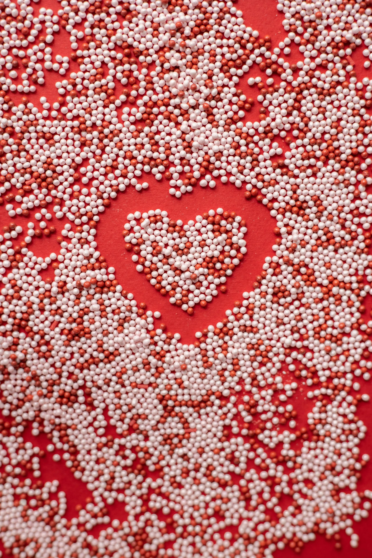 a heart made out of sprinkles on a red surface, by Georgina Hunt, pexels, pointillism, pearls, red and white neon, in 4k, camouflage made of love