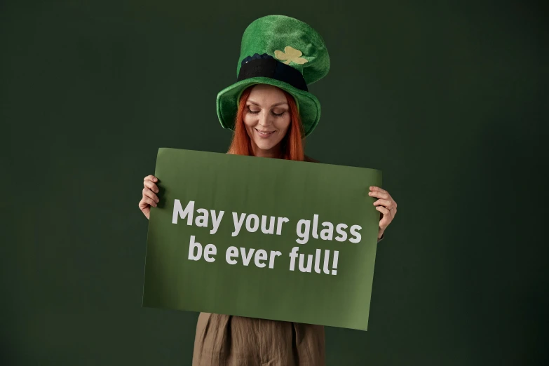 a woman holding a sign that says may your glass be ever full, by Eamon Everall, pixabay, wearing green tophat, high quality product photo, instagram post, irish