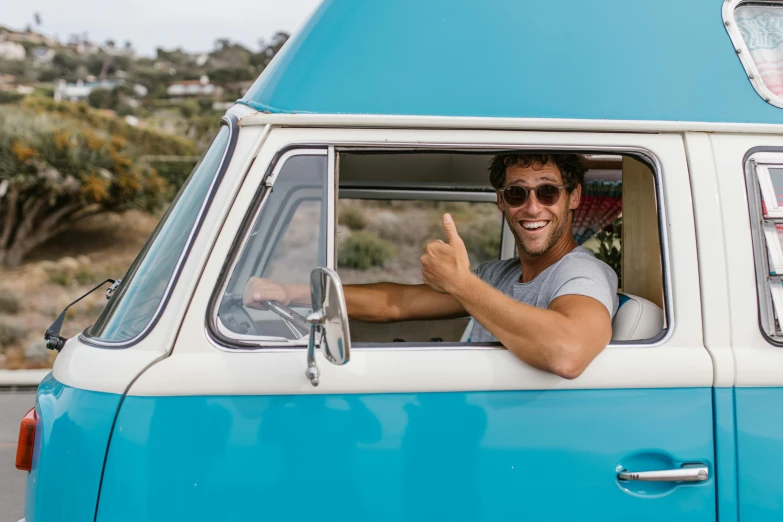 a man sitting in the driver's seat of a blue and white van, pexels contest winner, thumb up, kombi, nate berkus, classic gem