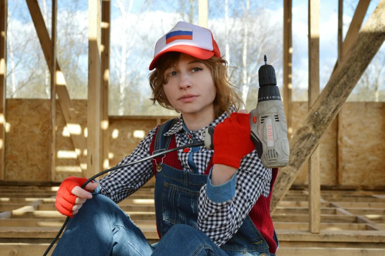 a woman sitting on the ground with a drill in her hand, a portrait, inspired by Norman Rockwell, pixabay, still from stranger things movie, cosplay photo, russian constructivism, teen boy