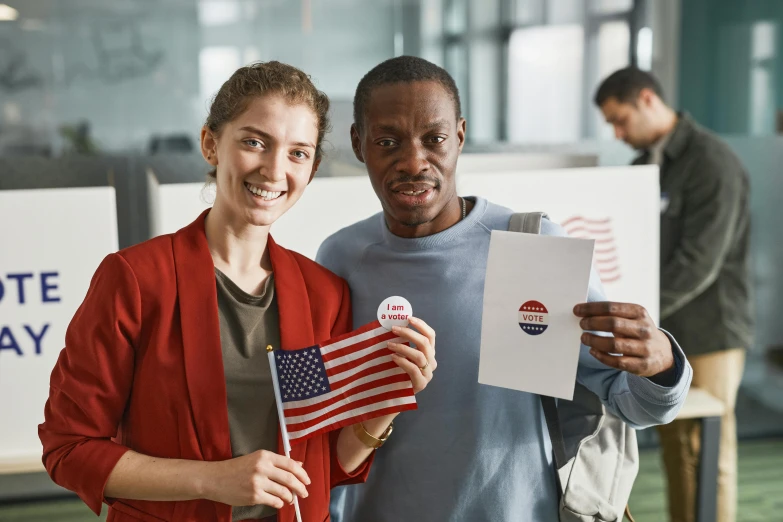 a man standing next to a woman holding an american flag, a photo, educational, holding an ace card, mix of ethnicities and genders, student