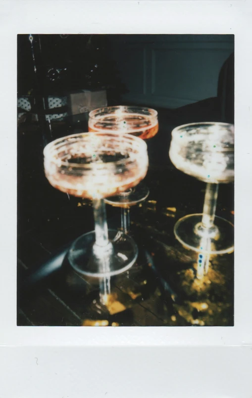 a group of wine glasses sitting on top of a table, a polaroid photo, inspired by Nan Goldin, unsplash, refracted sparkles, detailed color scan, champagne, medium format