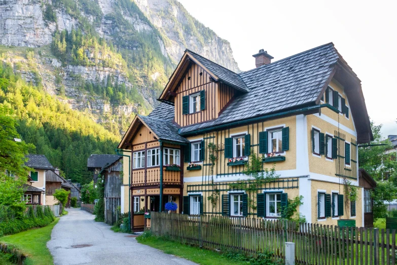 a yellow and white house with a mountain in the background, by Franz Hegi, pexels contest winner, art nouveau, timbered house with bricks, avatar image, vacation photo, exterior photo