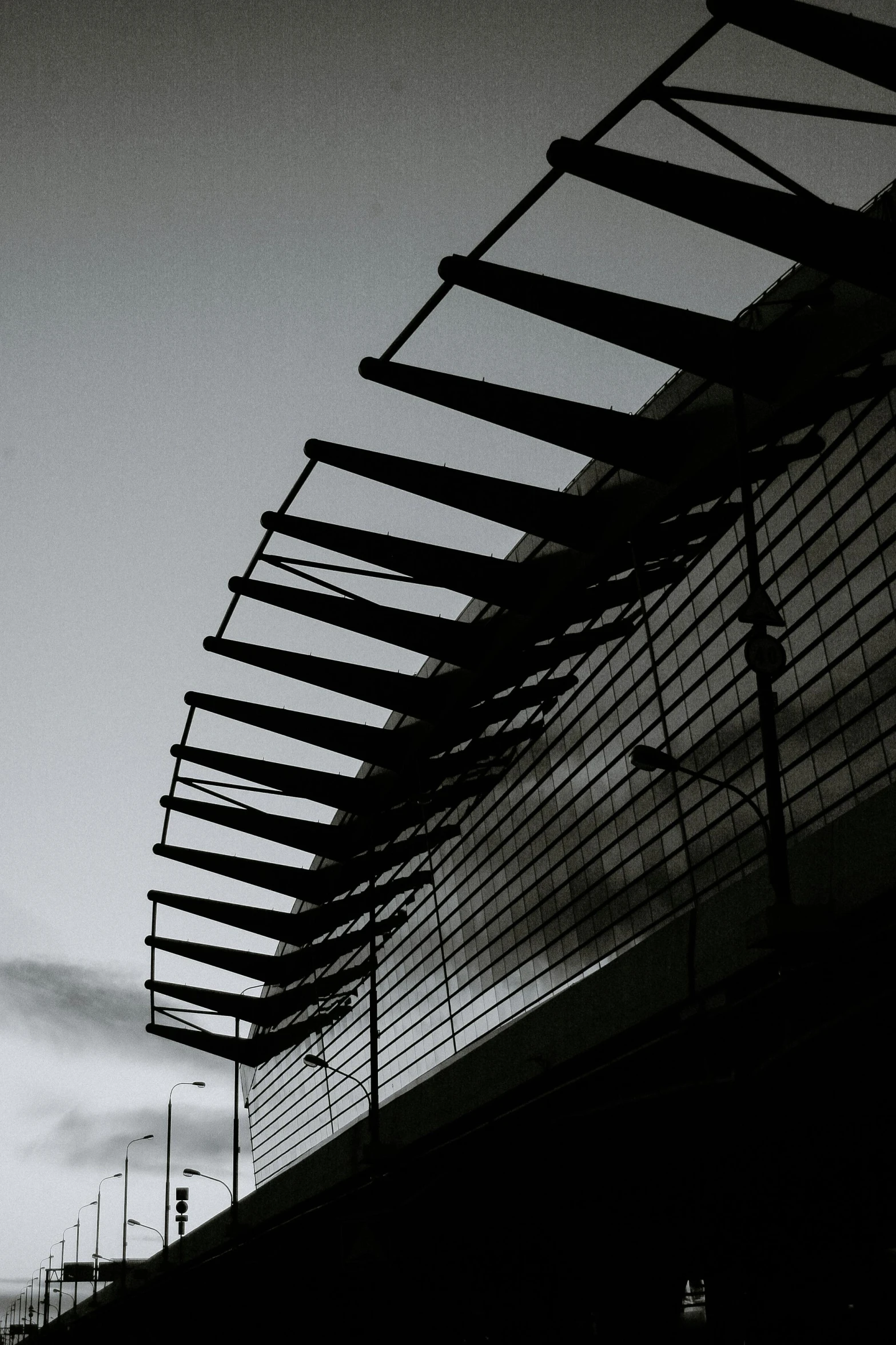 a black and white photo of a train station, inspired by Pierre Soulages, unsplash, brutalism, awnings, sky bridge, metal wings, spines