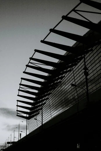 a black and white photo of a train station, inspired by Pierre Soulages, unsplash, brutalism, awnings, sky bridge, metal wings, spines