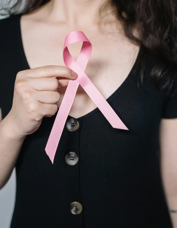 a woman in a black shirt holding a pink ribbon, a cartoon, trending on pexels, bra strap, high resolution photo, multiple stories, medical image