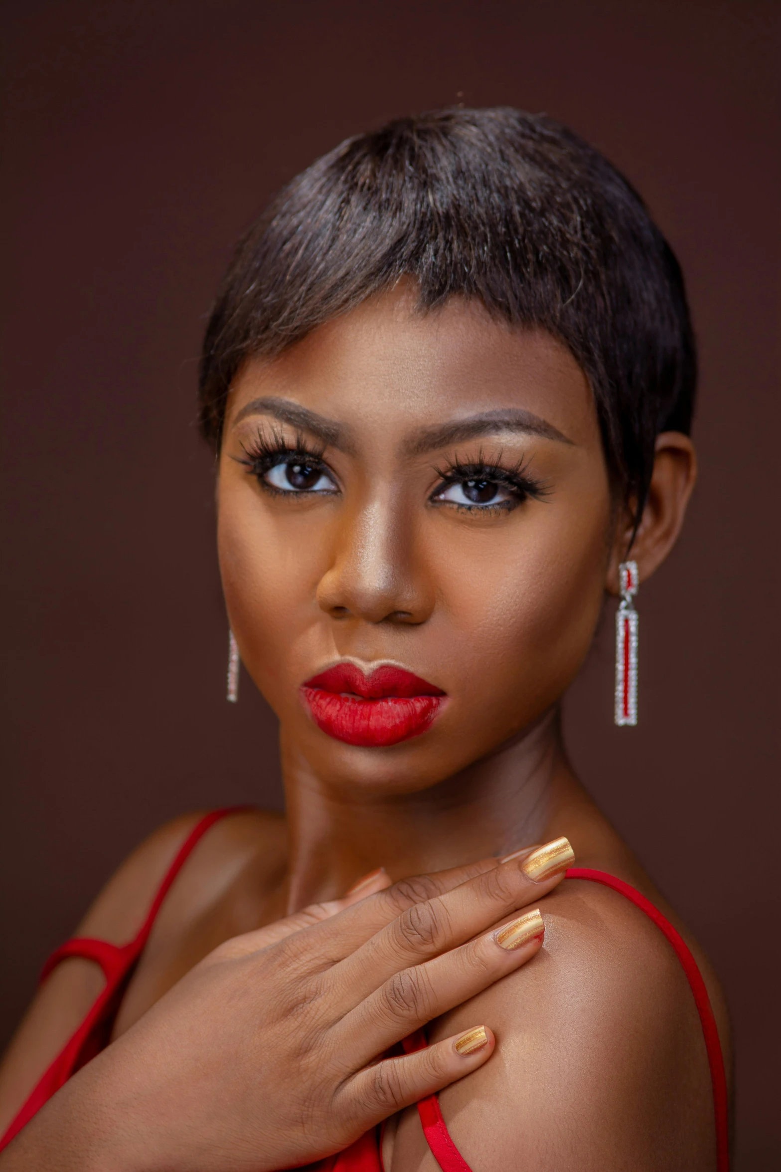 a woman in a red dress posing for a picture, an album cover, inspired by Chinwe Chukwuogo-Roy, photorealism, closeup headshot portrait, short black pixie like hair, photoshoot for skincare brand, brown skin. light makeup